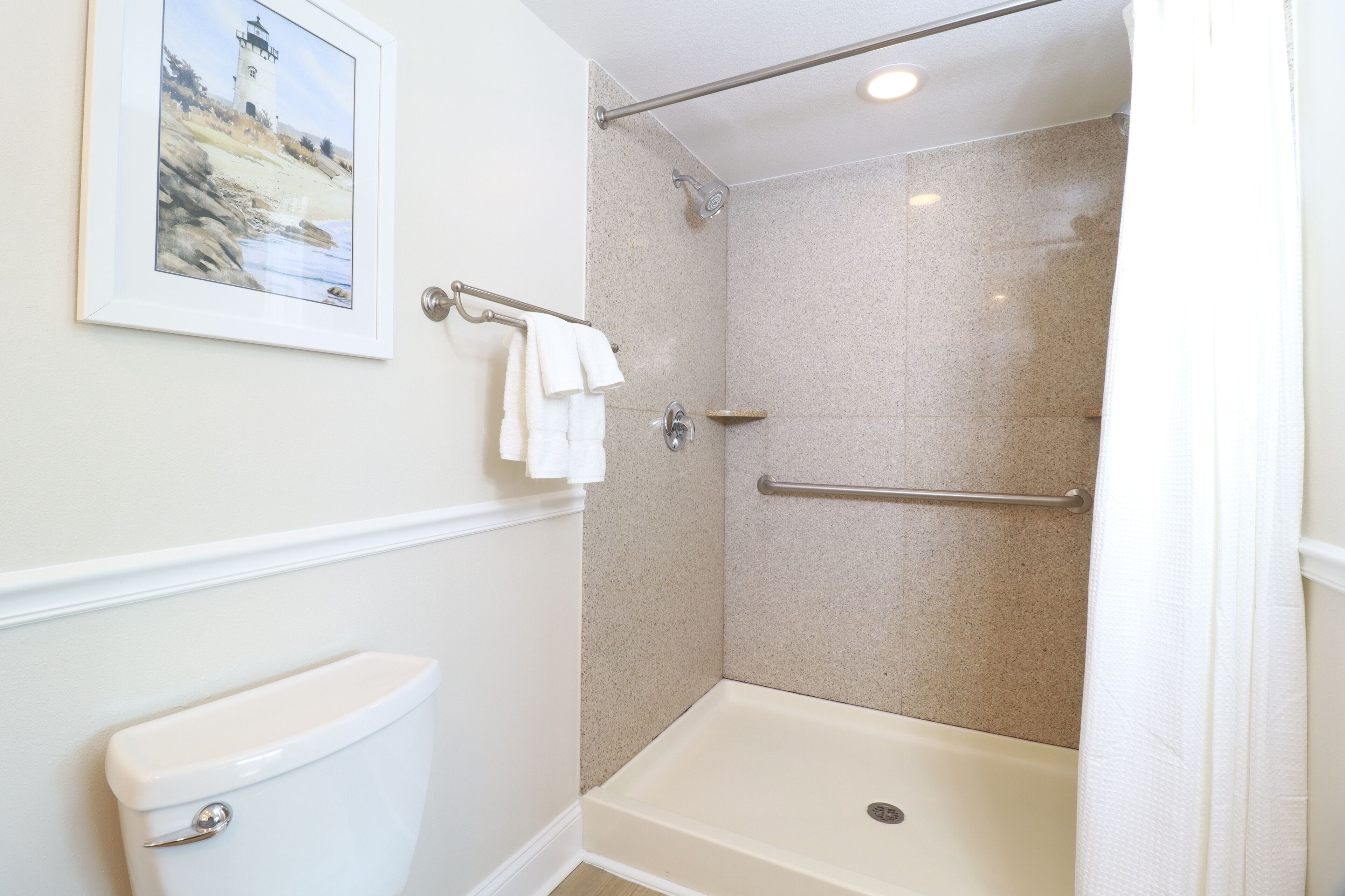 Een badkamer met een douche, toilet en een inlijsting foto aan de muur.