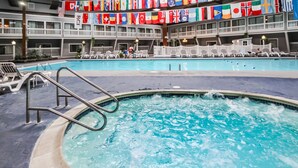 An indoor swimming pool with lounge chairs and flags. - The Cove at Yarmouth Resort (West Yarmouth)