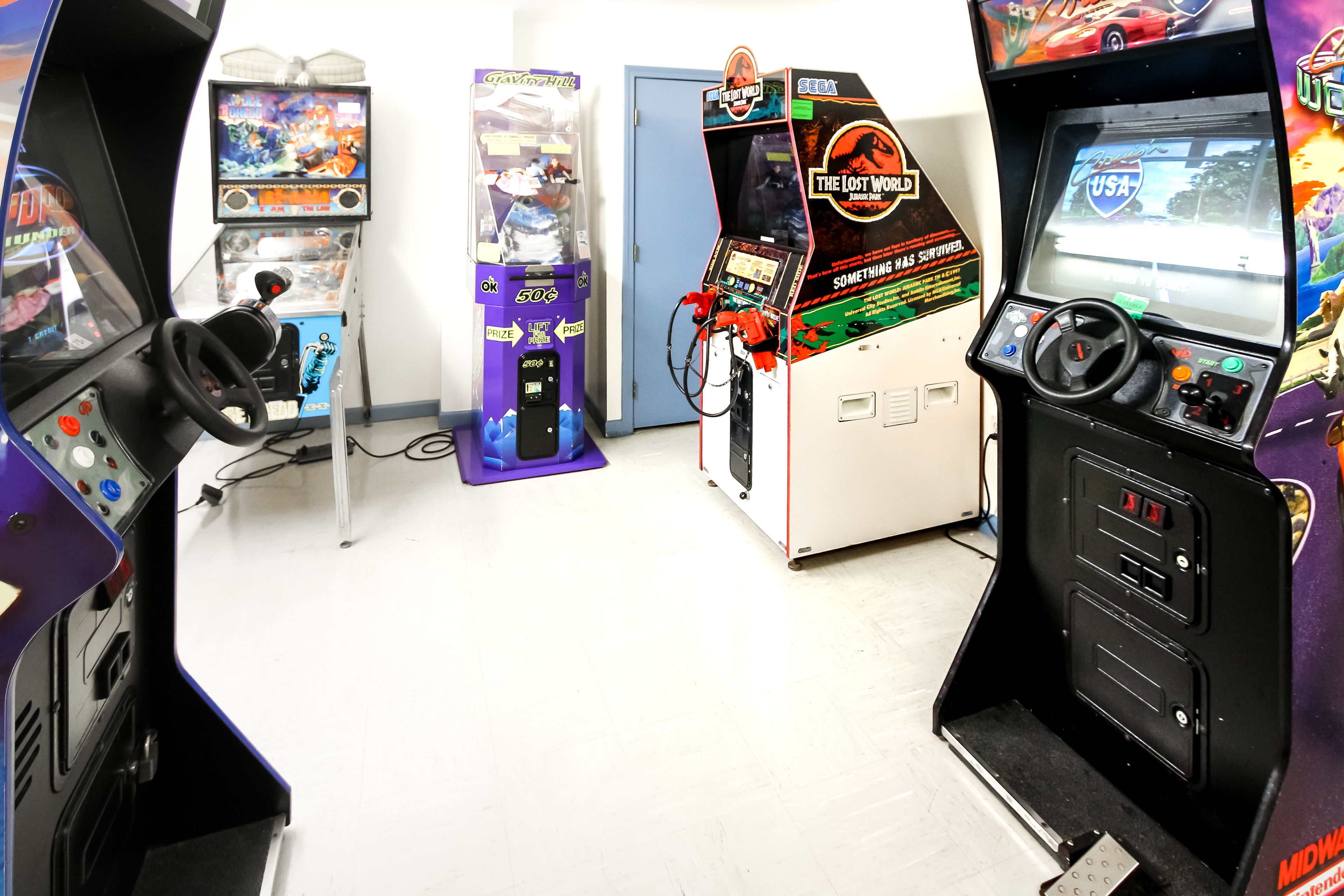 Ein Raum mit Spielautomaten, darunter 'The Lost World' und 'Midway'.