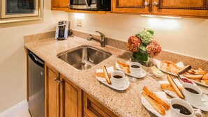 A kitchen with a granite countertop, stainless steel sink, wooden cabinets, a microwave, and a coffee maker. - The Cove at Yarmouth Resort (West Yarmouth)