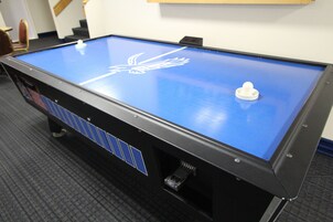 Uma mesa de bilhar com tecido aveludado azul e um logotipo de pássaro branco.