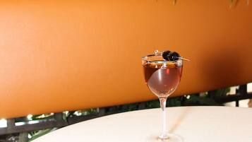 A cocktail glass on a white table with a plant in the background.