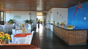 A hotel lobby with white tables and chairs, a reception desk, and a wooden ceiling. - Pousada Portal do Prado (Prado)