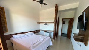A hotel room with a large bed, a desk, a television, and a bathroom visible through an open door. - Pousada Portal do Prado (Prado)