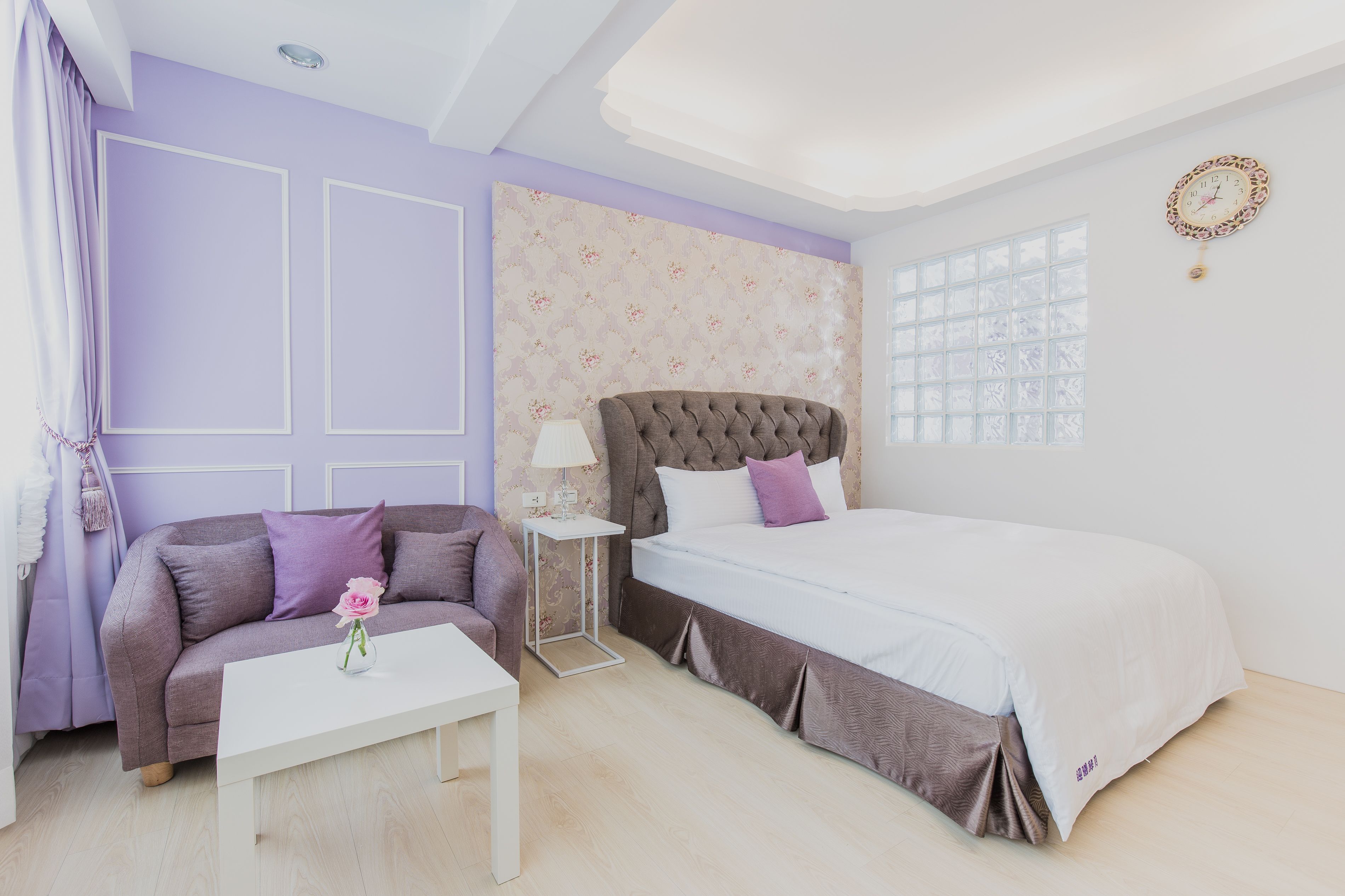 A bedroom with a bed, a sofa, a small table, and a nightstand.