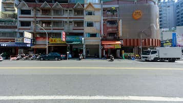 Vista de una calle con edificios de varios pisos, comercios y vehículos estacionados.