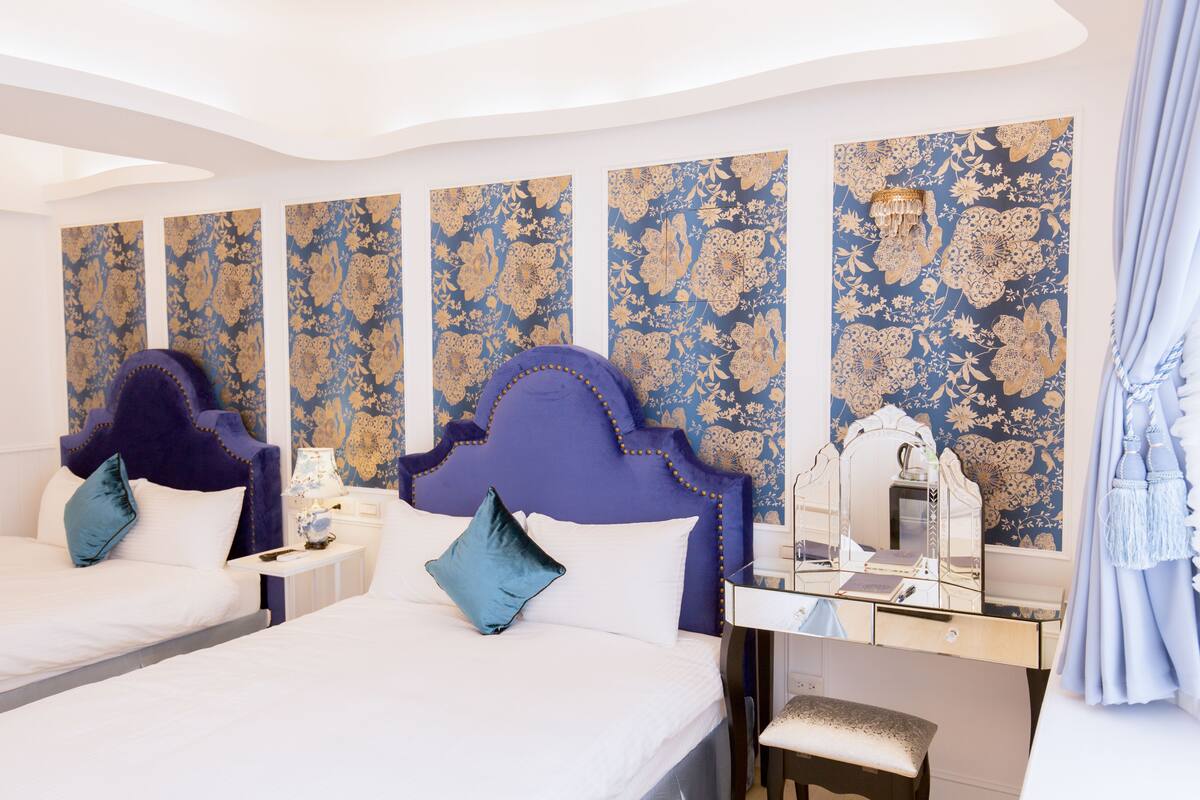 A hotel room with two beds, a vanity, and a mirror.