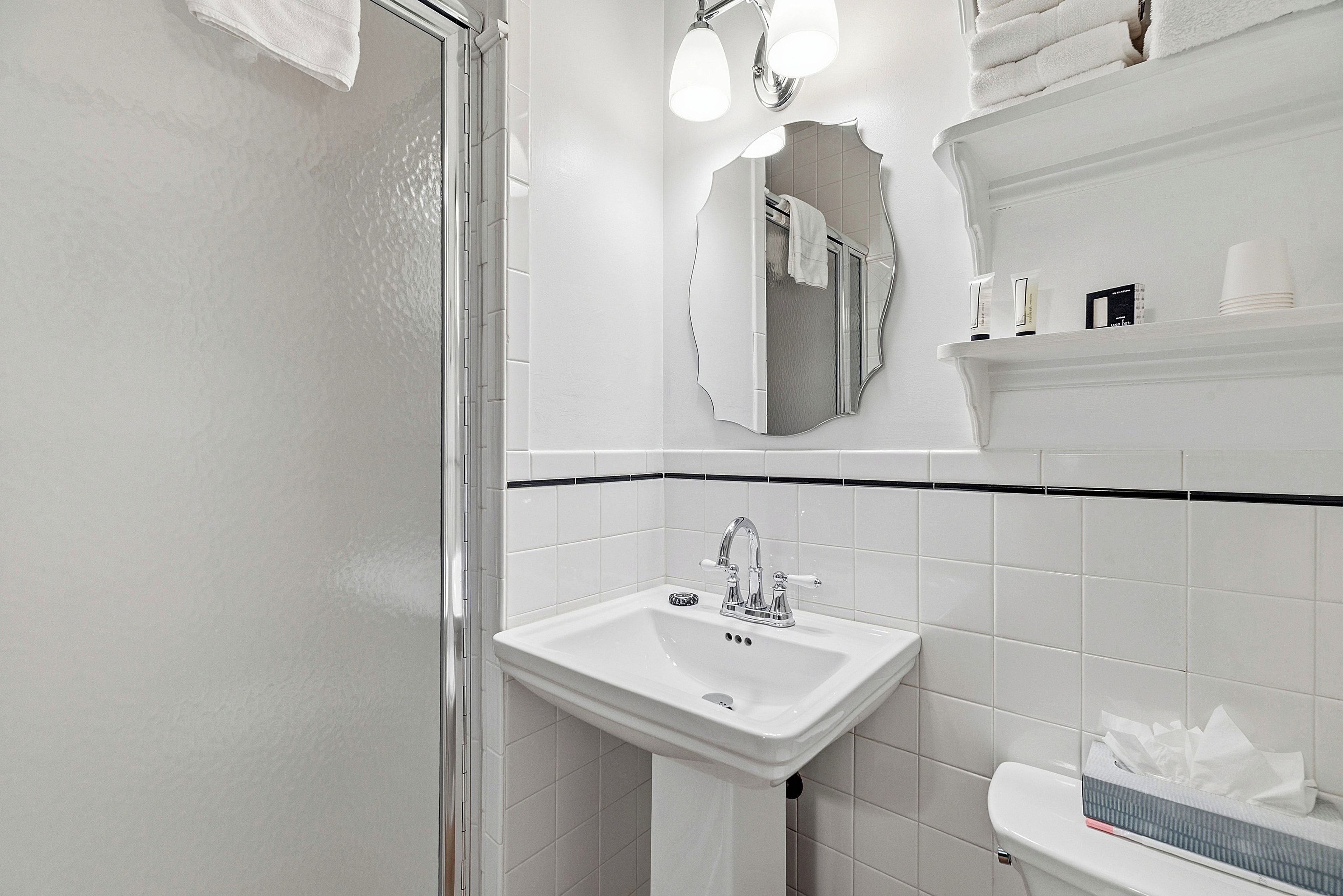 A bathroom with a white sink, a mirror, and a shower.