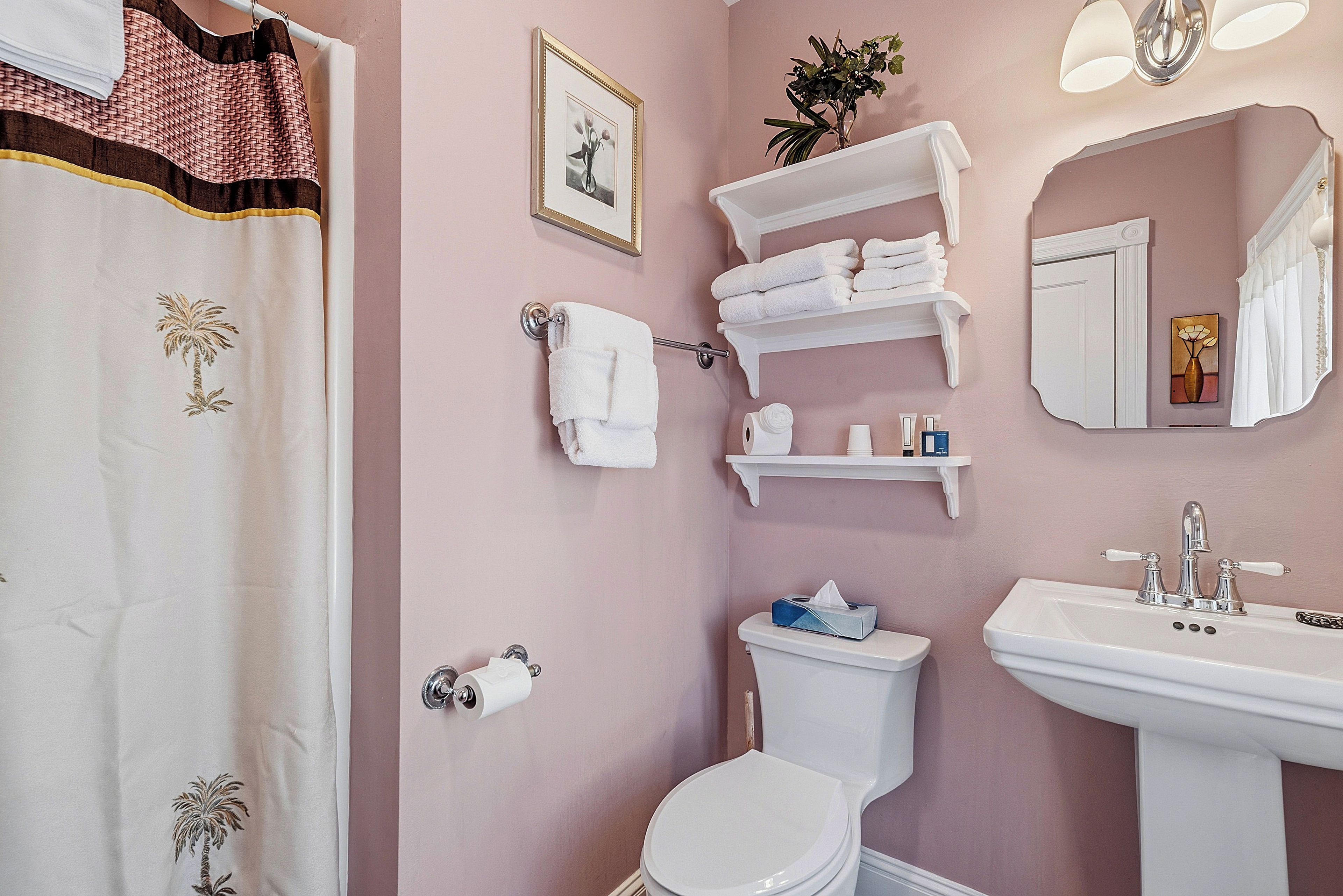 A bathroom with a toilet, sink, towel rack, and shelves with toiletries.
