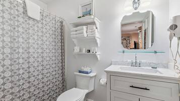 Une salle de bain équipée de toilettes, d’un lavabo, d’un miroir et d’un rideau de douche.
