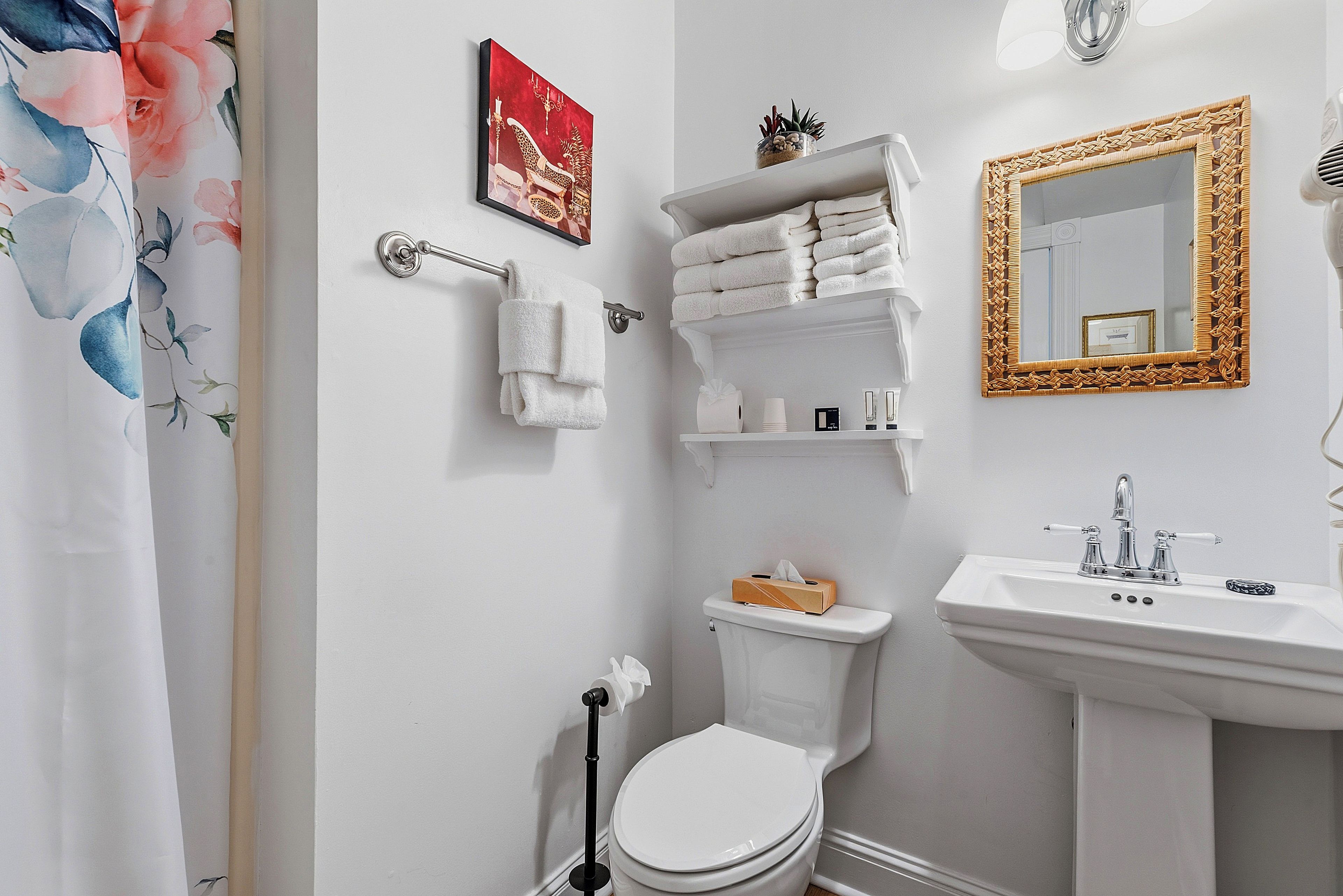 A bathroom with a toilet, sink, towel rack, and a mirror with a decorative frame.