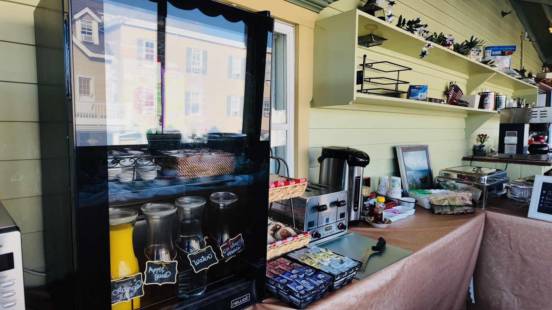 En café med et glasmontre fyldt med drikkevarer og en kaffemaskine.