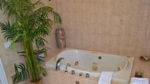 A bathroom with a bathtub, a potted plant, and a stack of towels. - The Ocean Plaza (Ocean Grove)