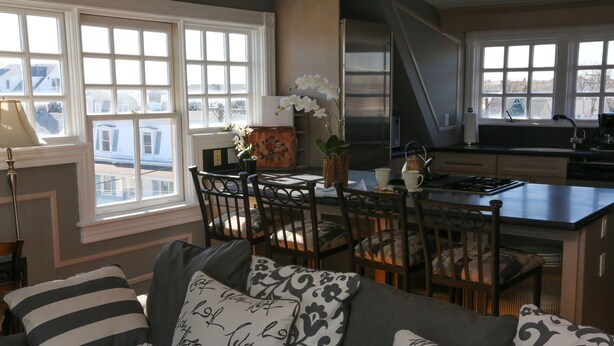 A cozy kitchen with a dining area, large windows, and a modern stove. - The Ocean Plaza (Ocean Grove)