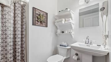 A bathroom with a toilet, sink, and shower area.