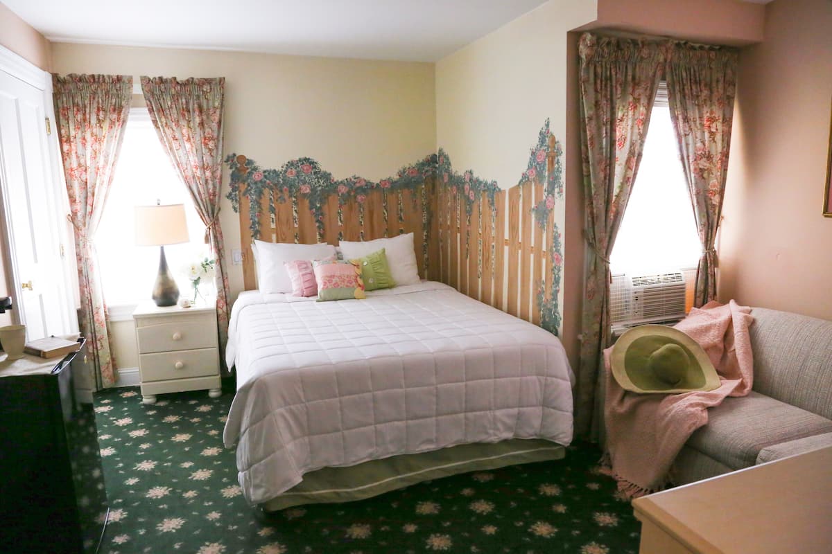 A bedroom with a bed, nightstand, dresser, and a window with curtains.