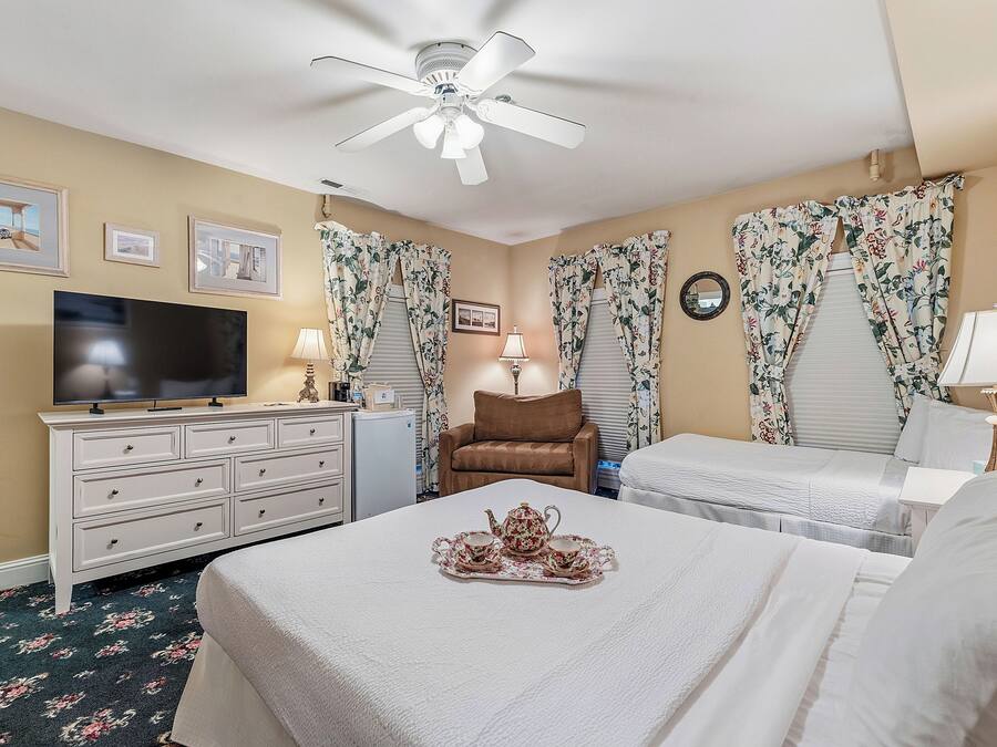 A hotel room with a bed, a television, a dresser, a chair, and a ceiling fan.