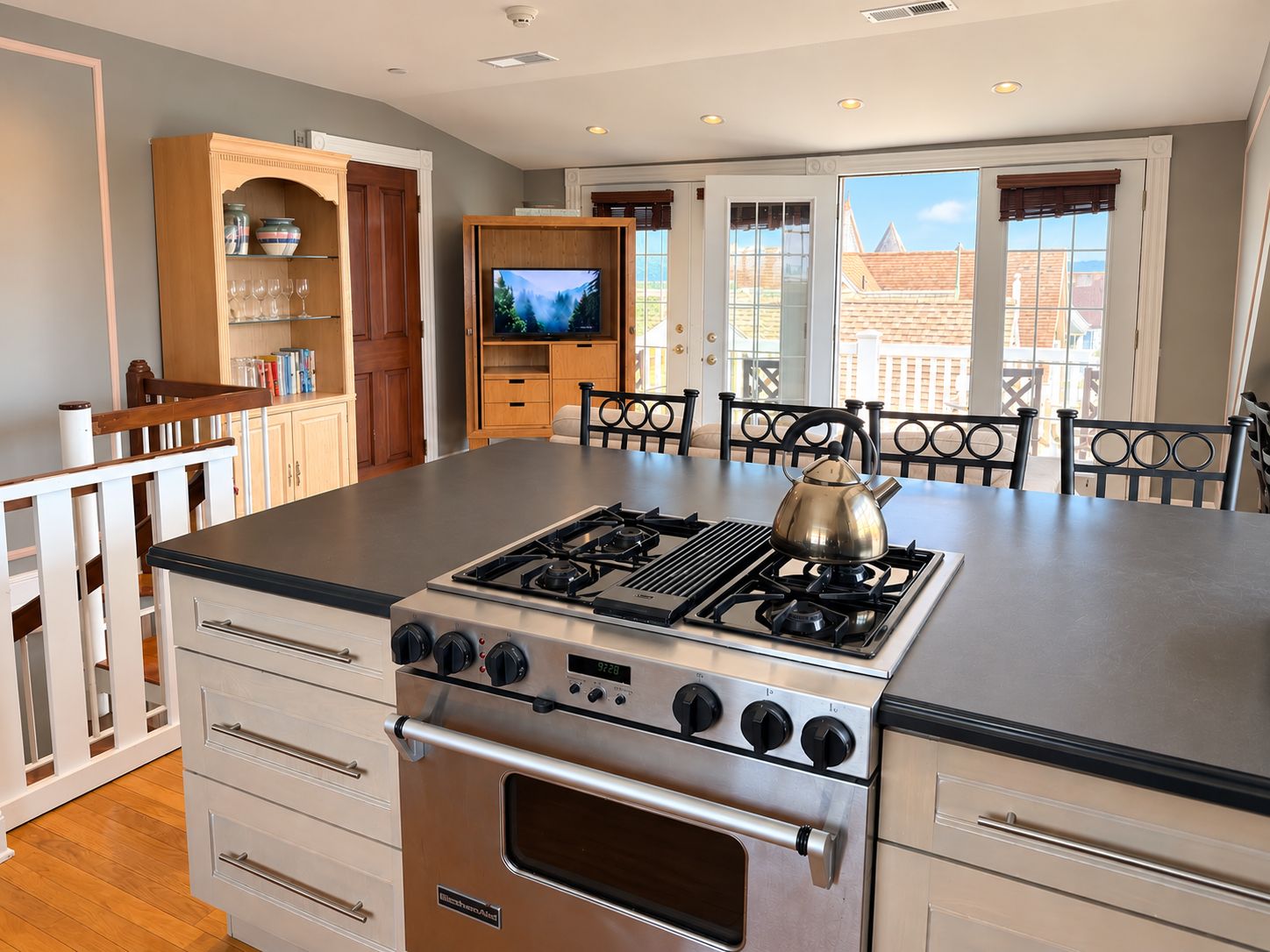 A modern kitchen with a central island, built-in oven, and a television on a cabinet.