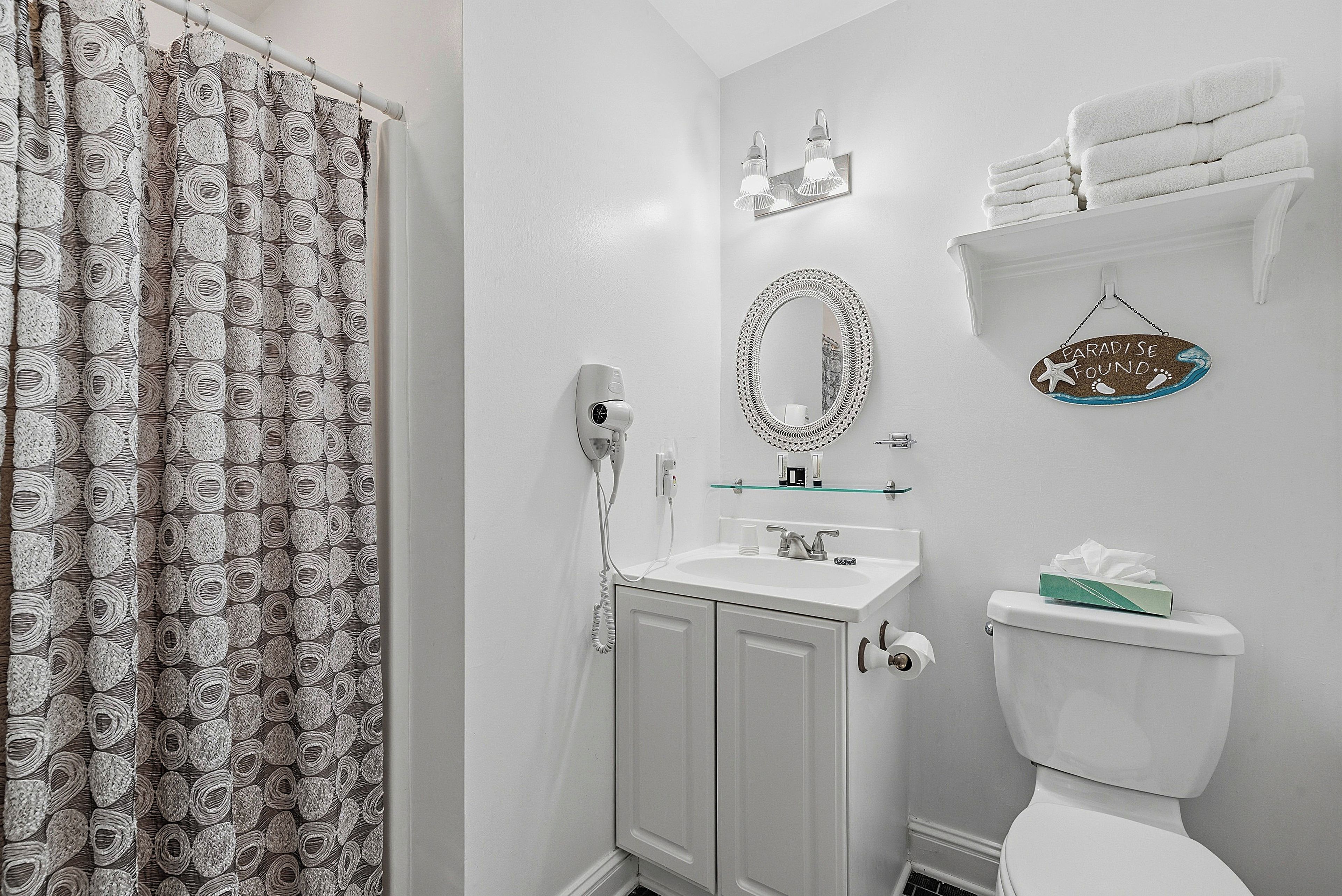 A bathroom with a shower, toilet, sink, and a towel rack.