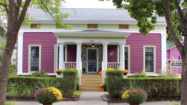 A two-story house with a front porch, numbered 209, and a well-maintained garden with potted plants. - The Blackberry Inn Bed & Breakfast (Watkins Glen)