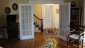 A living room with wooden flooring, a bookshelf, a chair, and a television. - The Blackberry Inn Bed & Breakfast (Watkins Glen)