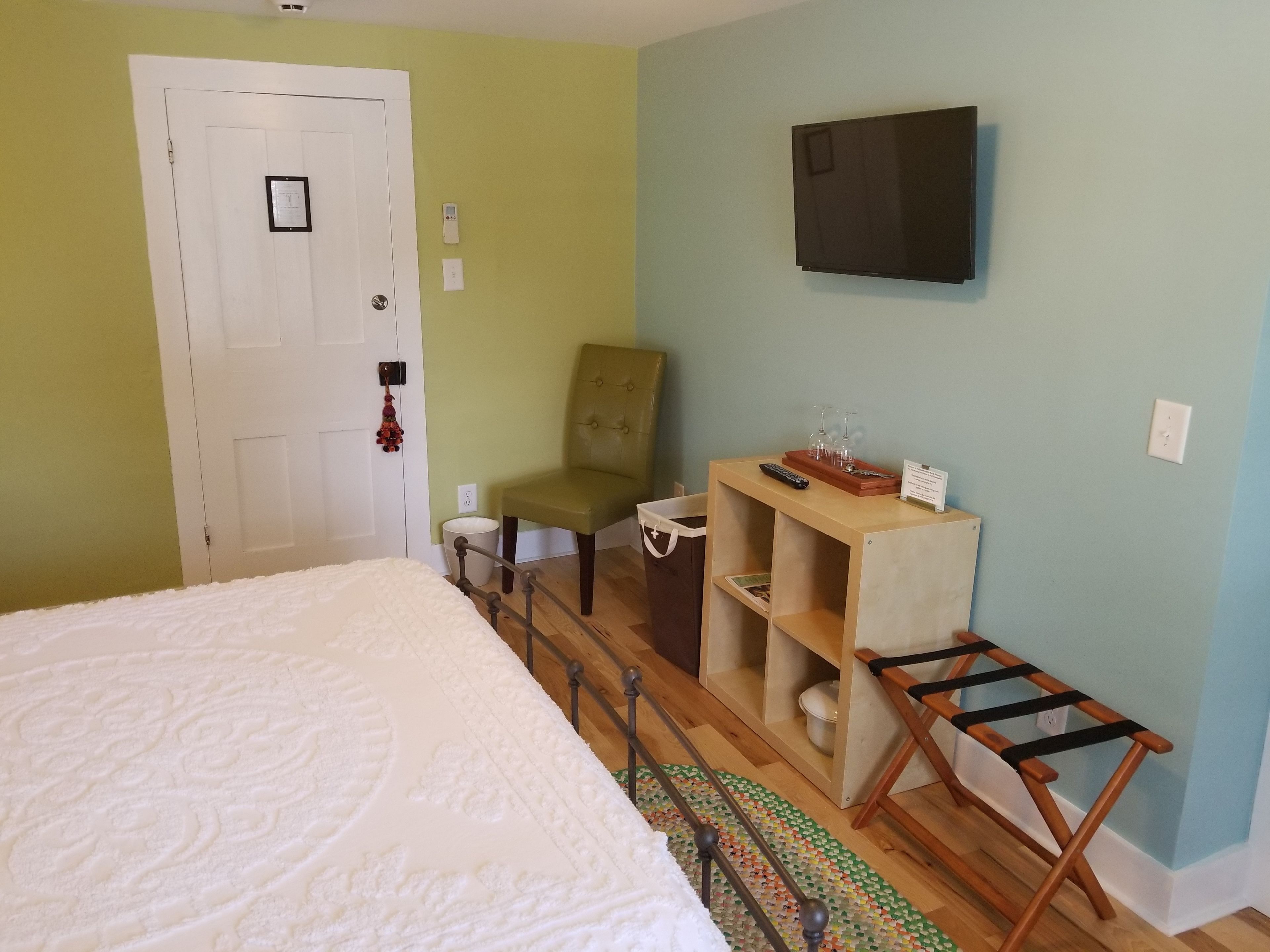 Une chambre à coucher avec un lit, une chaise, un téléviseur et une petite table sur laquelle se trouvent divers objets.