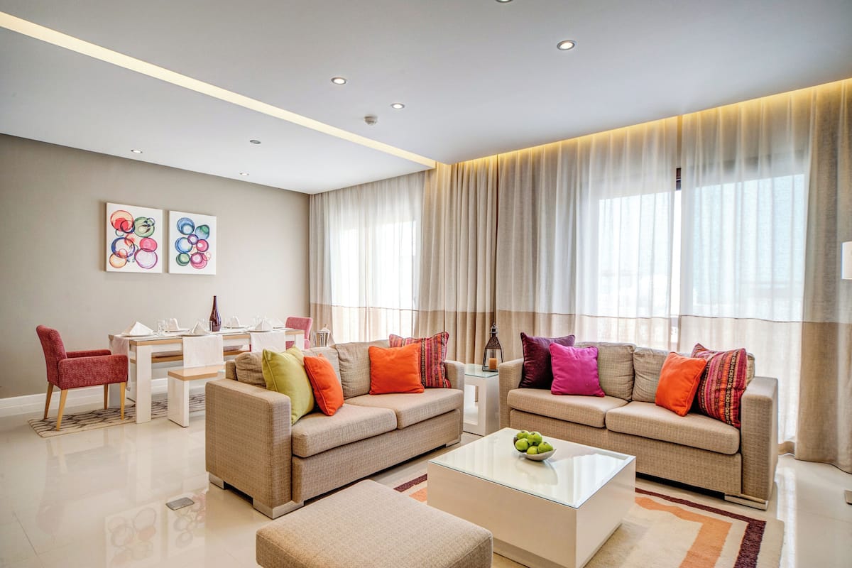 A modern living room with two sofas, a coffee table, and a dining area with a table and chairs.