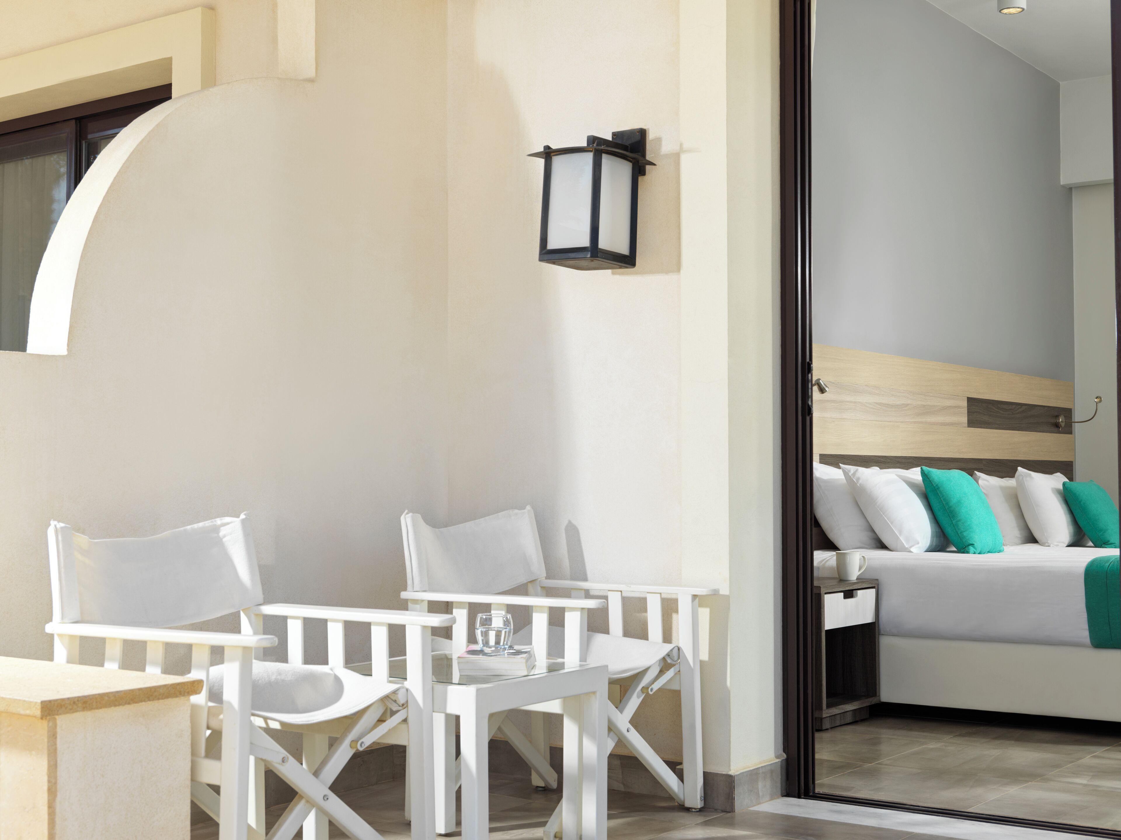 A modern hotel room with a bed, a nightstand, and a seating area with two chairs and a table.