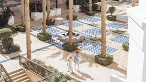 A courtyard with palm trees, patterned tiles, and a staircase. - Ancient Sands Golf Resort and Residences (El Gouna)