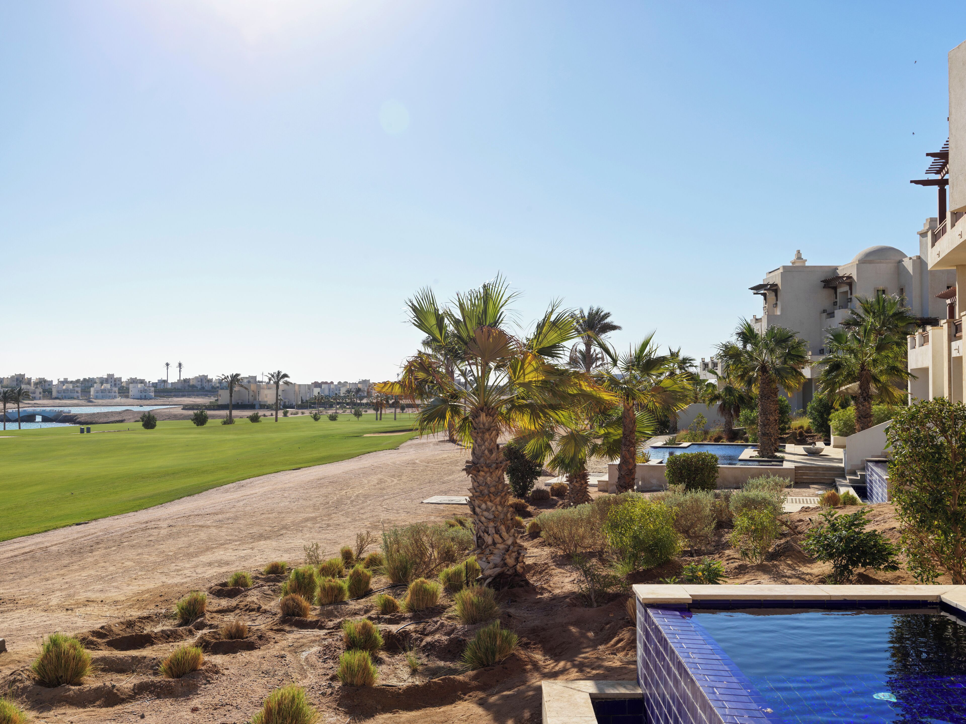 A pool area with a view of a golf course and a city skyline in the background.