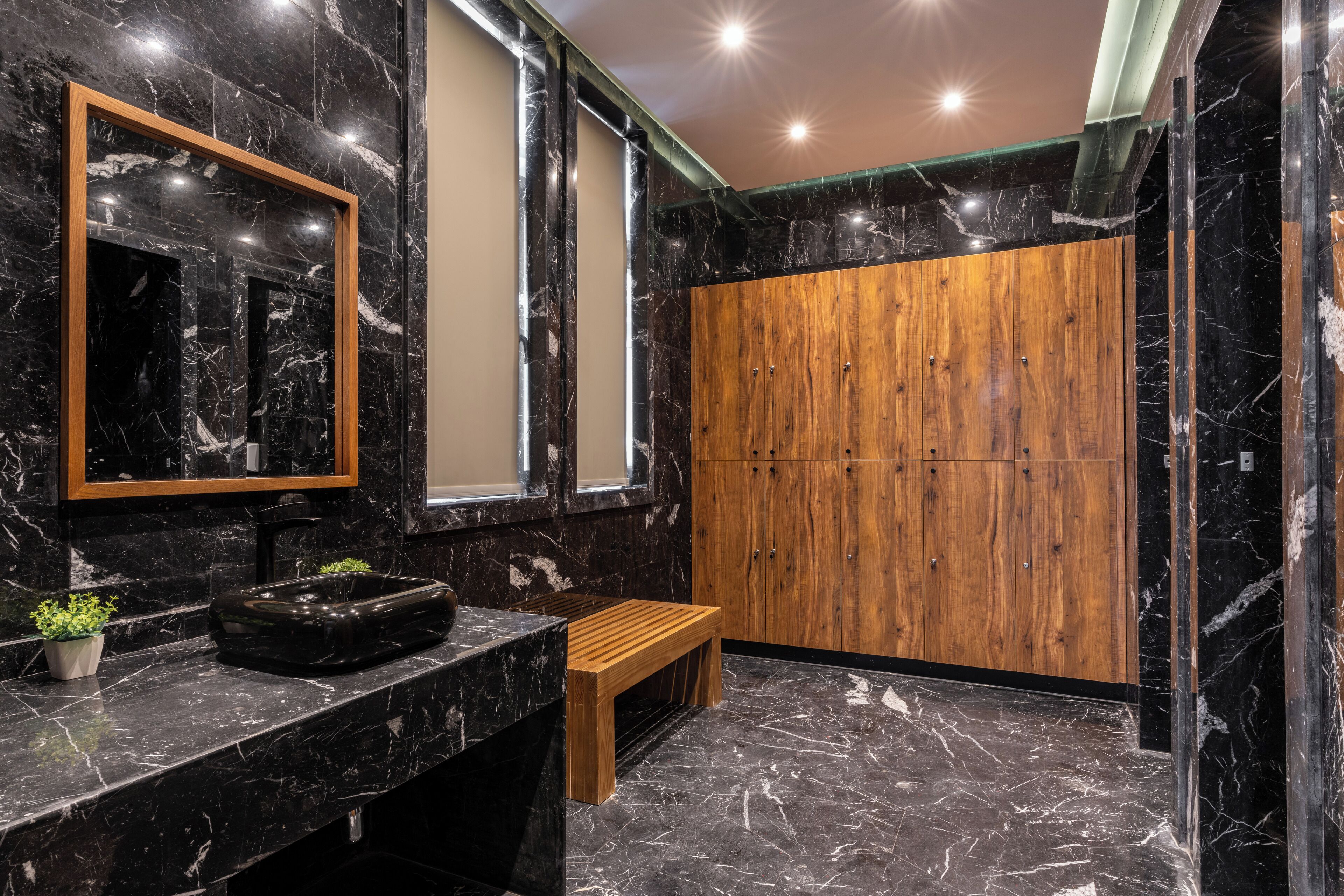 A bathroom with a marble sink, wooden bench, and a wooden wardrobe.
