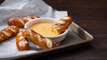 Pretzelstengels met dipsaus op een schaal.