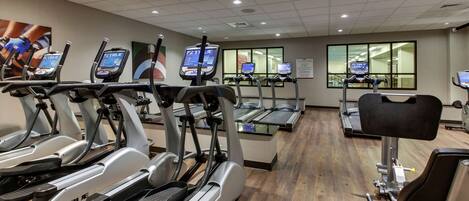 A gym with multiple treadmills, ellipticals, and a weight machine.