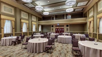 Un salón de conferencias con varias mesas redondas, sillas y un balcón con vistas al salón.