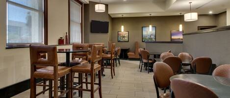 A restaurant with wooden chairs and tables, a large window, and artwork on the walls.