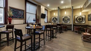 Un restaurante con mesas y sillas altas, un menú en una pizarra y letras A, B, C enmarcadas en la pared.