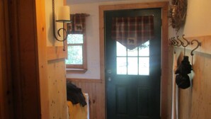 A wooden door with a window above it, a coat rack to the right, and a wall-mounted lamp to the left.