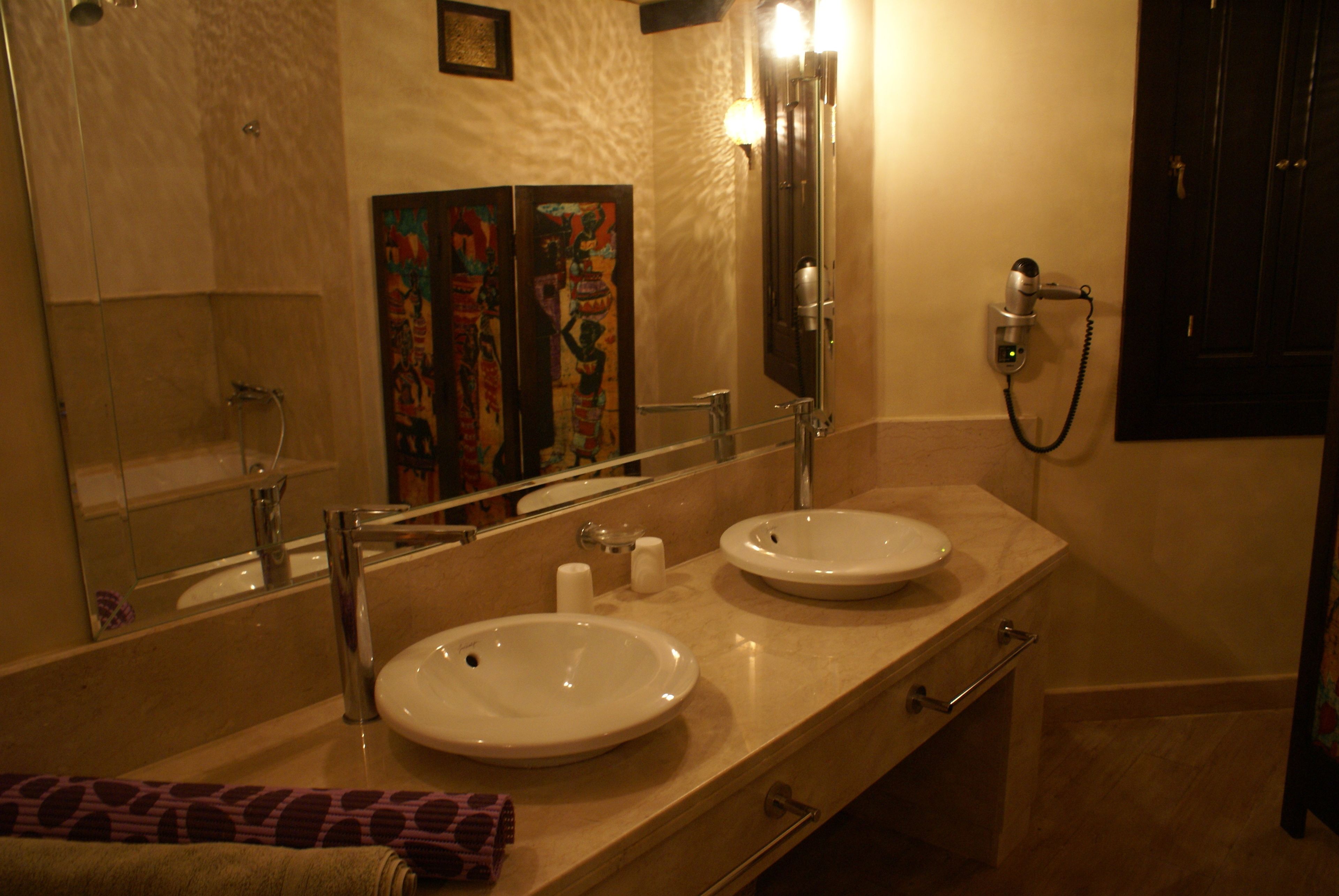 Un bagno con due lavandini, un ampio specchio, un portasciugamani e una doccia.