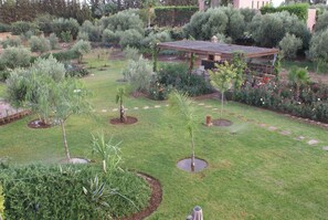 A landscaped garden with various plants, a gazebo, and a small building. - Kasbah Aâlma d'Or (Marrakech)