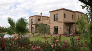 Una casa de dos pisos con piscina y un jardín lleno de plantas y flores.