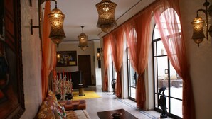 Una habitación con sofá, mesa y ventana con cortinas.