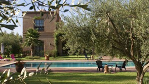 Zona de piscina con sillones de descanso y un edificio con balcón.