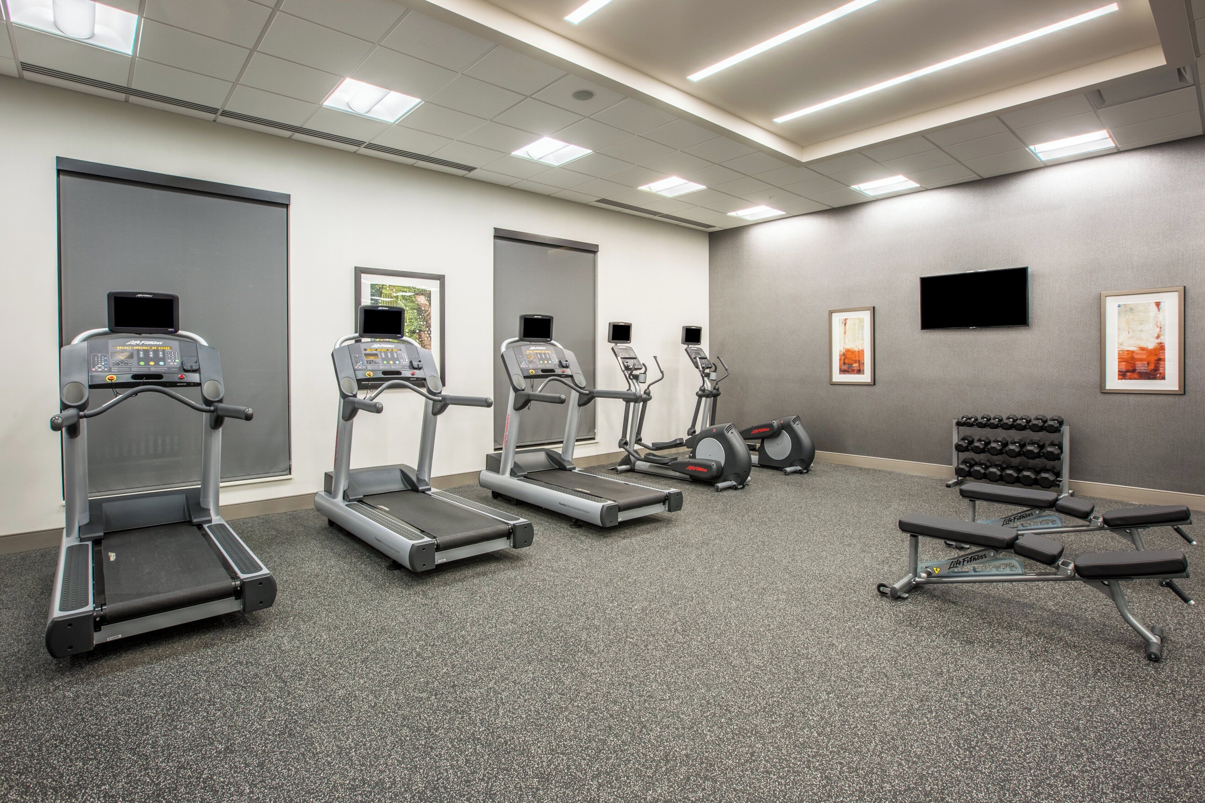 Une salle de sport équipée de tapis de course, de vélos elliptiques et de bancs de musculation.
