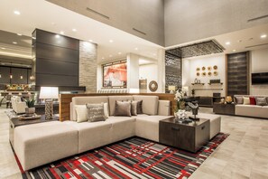 A spacious living area with a sectional sofa, a coffee table, and a patterned rug. - Holiday Inn Portland West - Hillsboro by IHG (Hillsboro)