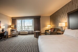 Een hotelkamer met een groot bed, een bureau, een stoel, een bank en een bijzettafeltje.