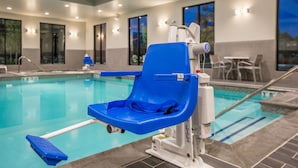 A poolside area with a blue pool chair, a pool lift, and a pool table.