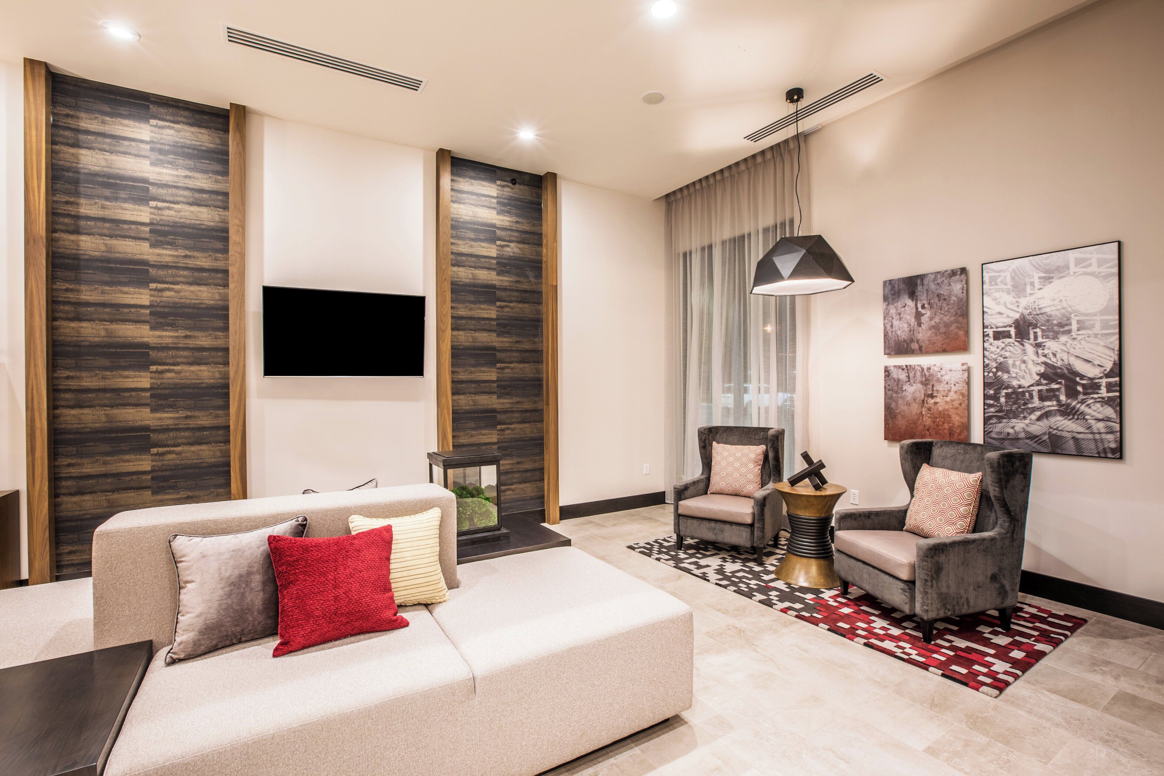 A modern living room with a sofa, armchairs, a coffee table, and a TV mounted on the wall.