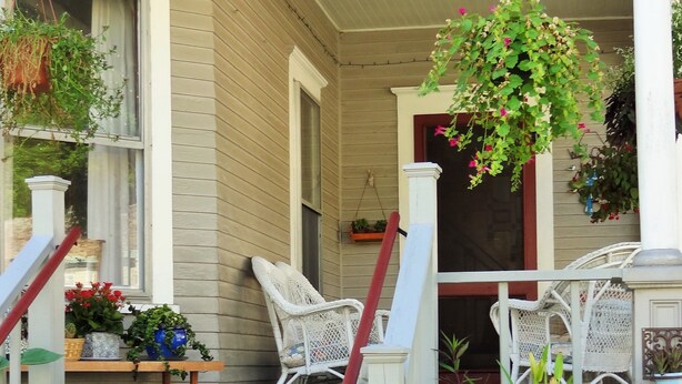 A porch with wicker chairs, potted plants, and a number '43' sign.