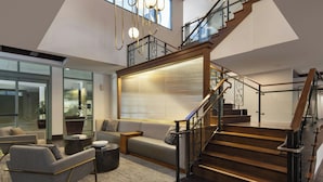 A spacious living area with a modern staircase, comfortable seating, and large windows. - Residence Inn Los Angeles Pasadena/Old Town (Pasadena)