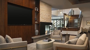 A modern living room with a flat-screen TV, comfortable seating, a staircase, and a view to the upper floor. - Residence Inn Los Angeles Pasadena/Old Town (Pasadena)